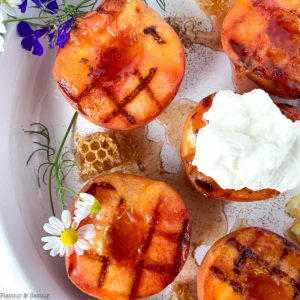 Close up view of grilled peaches topped with whipped cream