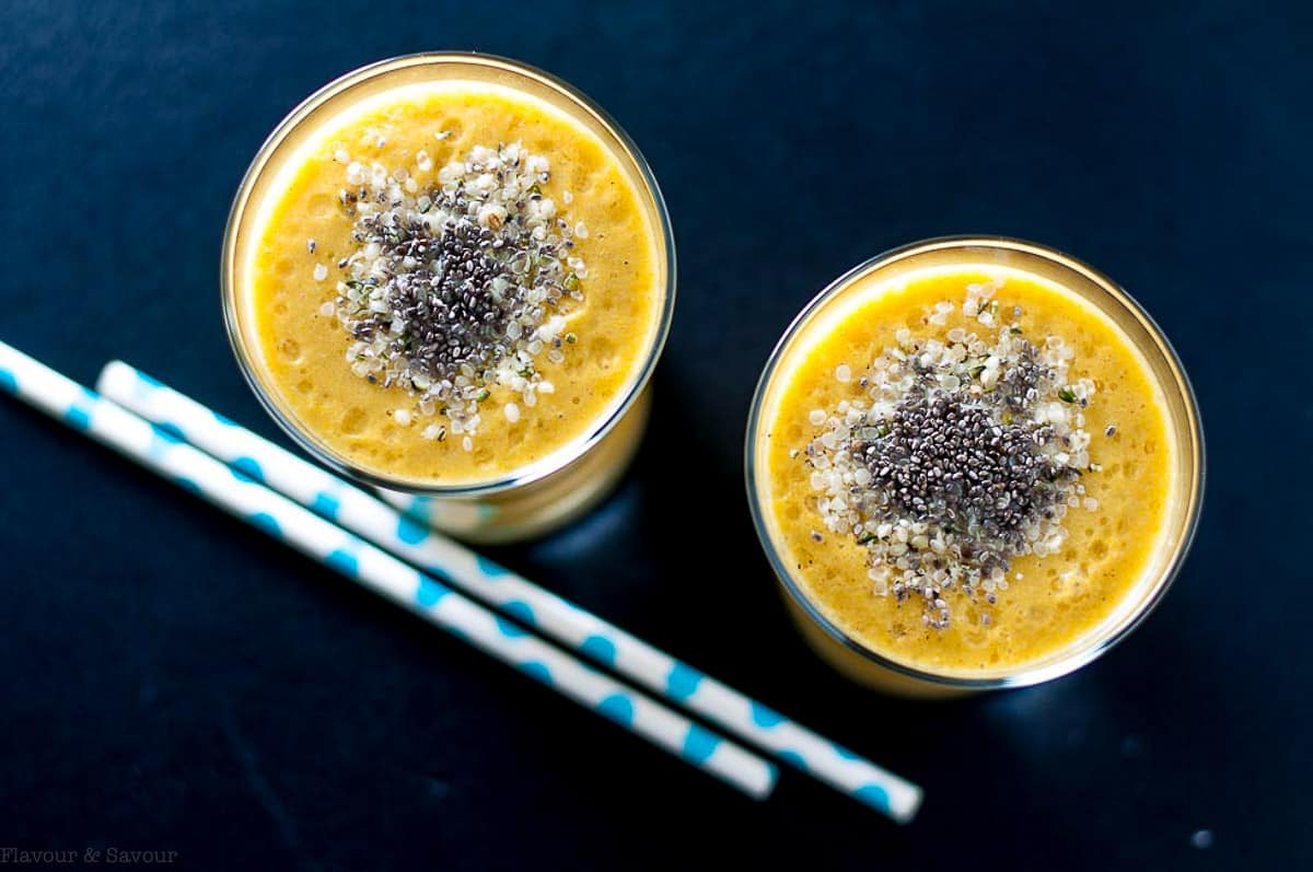 Overhead view of two glasses of tropical turmeric smoothie with chia and hemp hearts