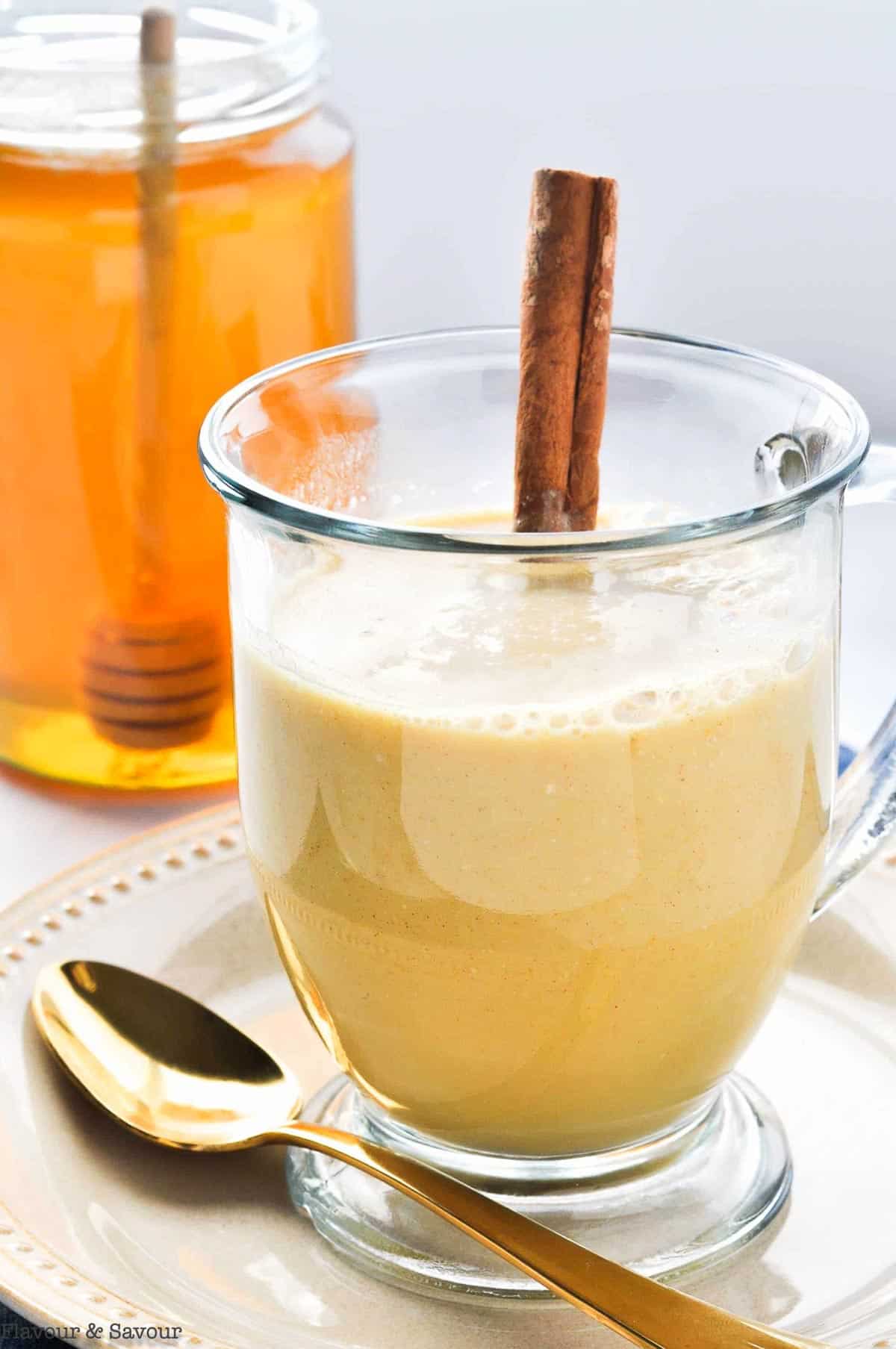 Warm Turmeric Cinnamon Milk in a glass mug with a cinnamon stick.