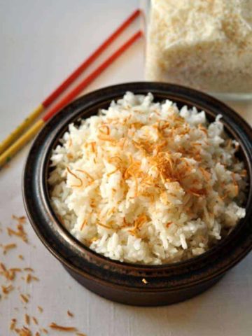 Thai Coconut Rice in a brown stoneware dish with chopsticks.