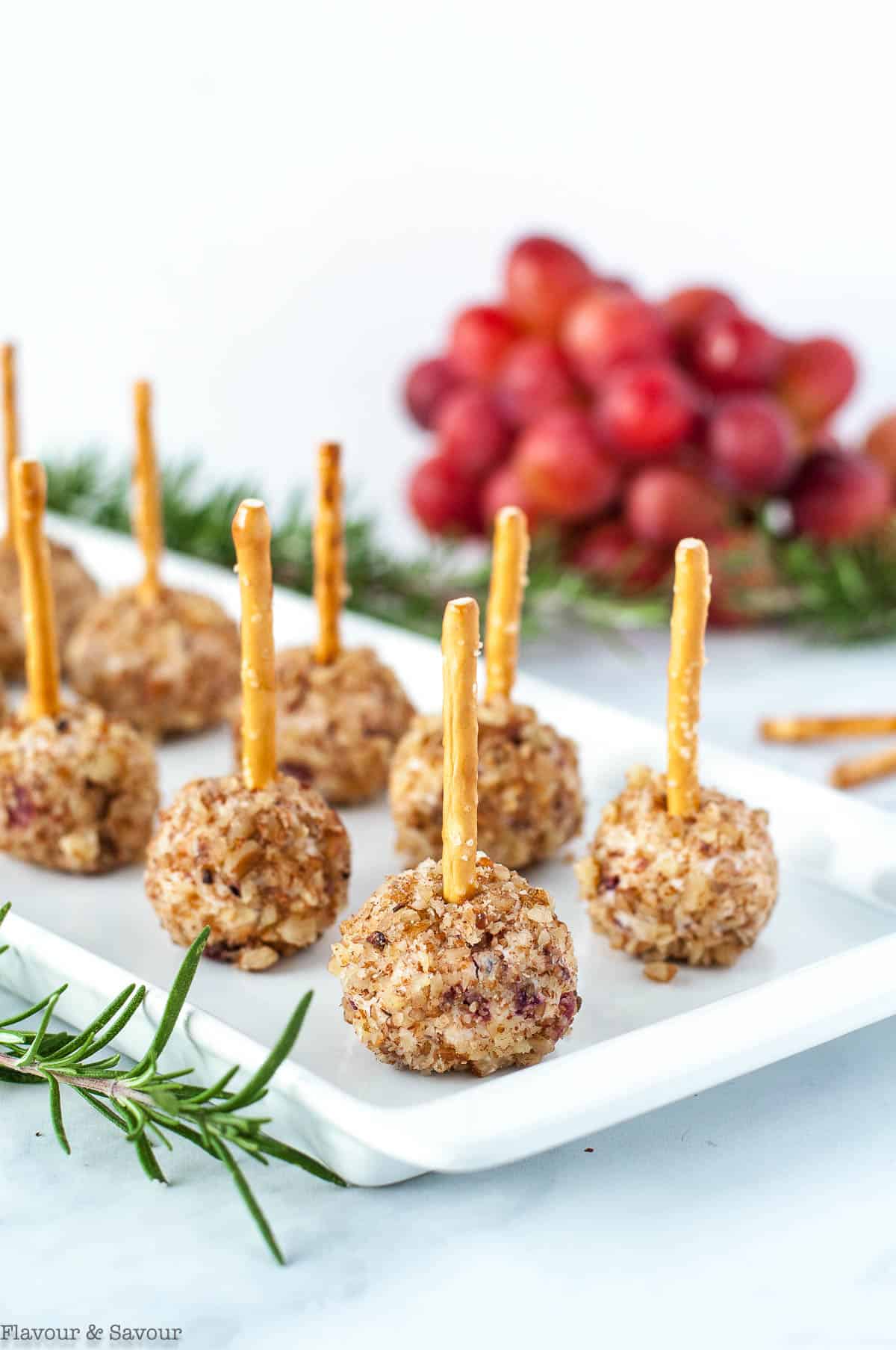 Mini Cheese Balls with pretzel sticks with grapes in the background
