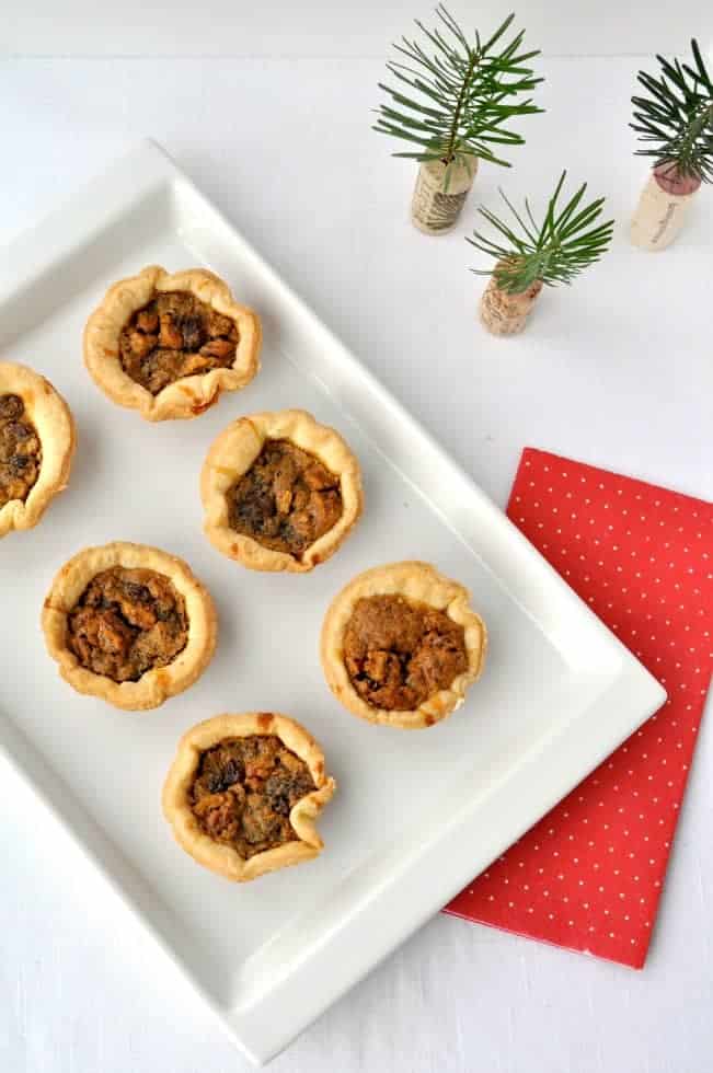 Overhead view of six Butter Tarts on a white dish.