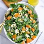A shallow bowl of kale salad with Cara Cara oranges and toasted almonds