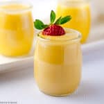 3 glasses of paleo lemon curd, one with a strawberry.