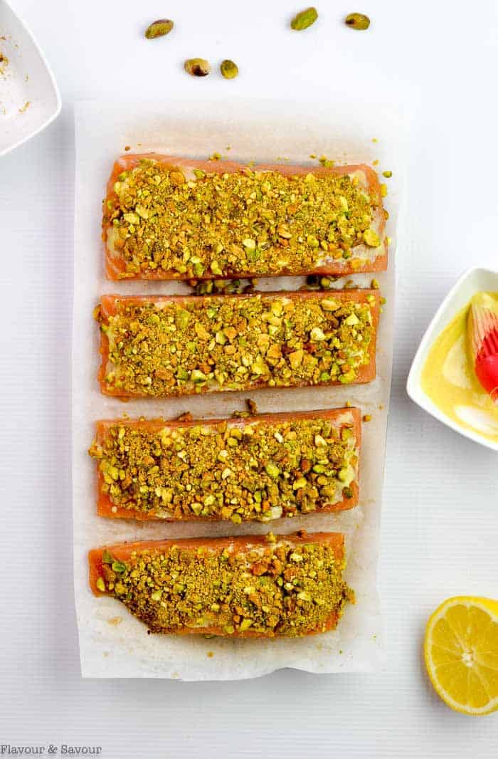 Pistachio-Crusted Salmon ready for the oven with crushed pistachios pressed into lemon-Dijon spread on top of salmon.