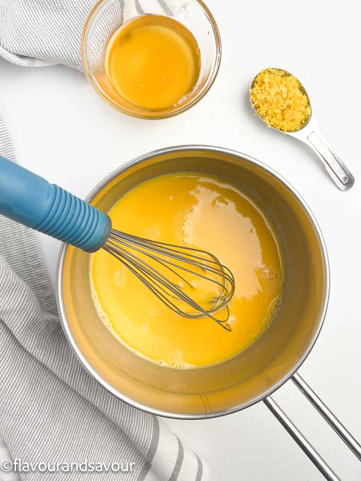 Whisking ingredients for lemon curd in a saucepan.