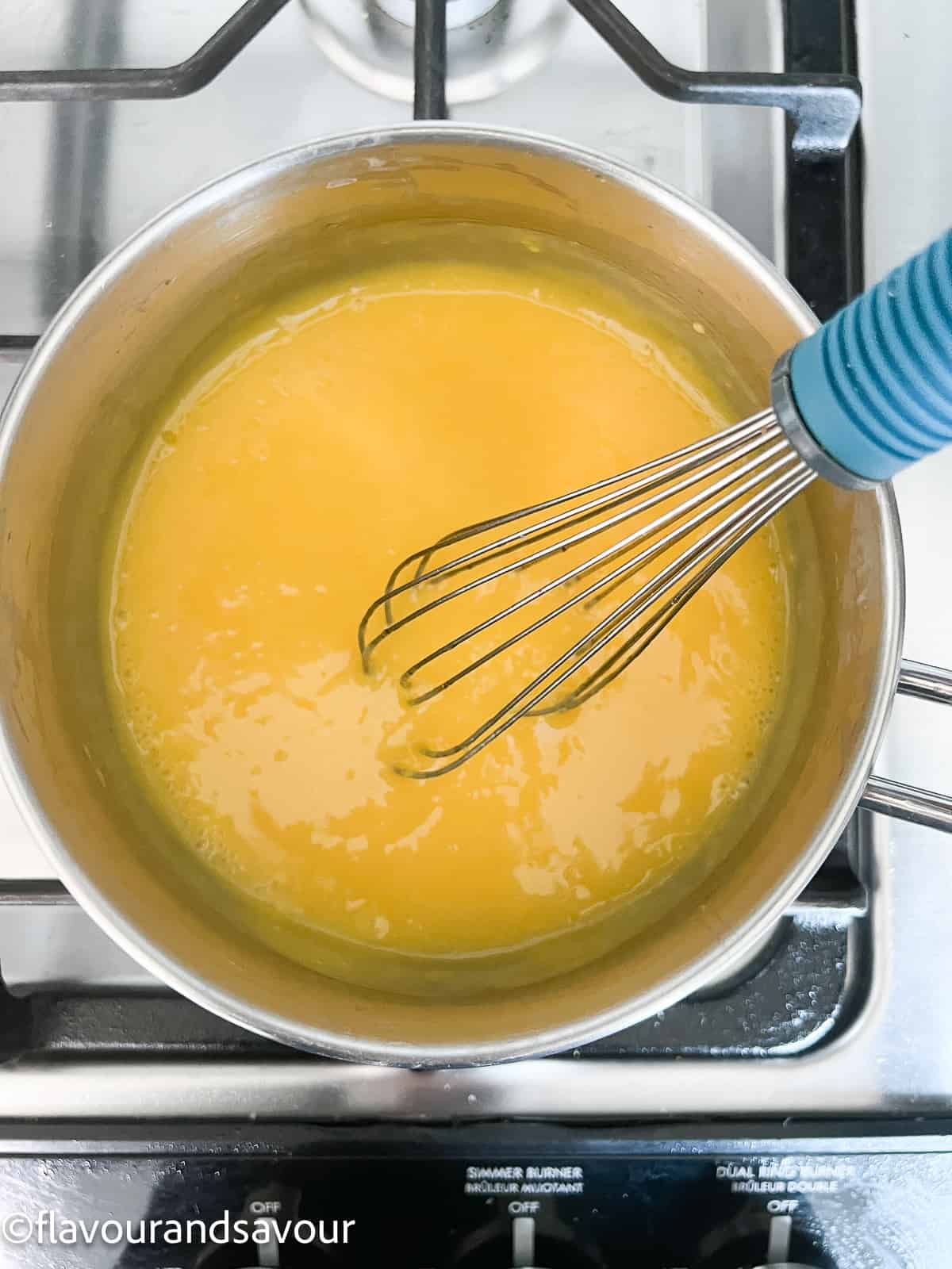 Lemon curd thickening in a saucepan.