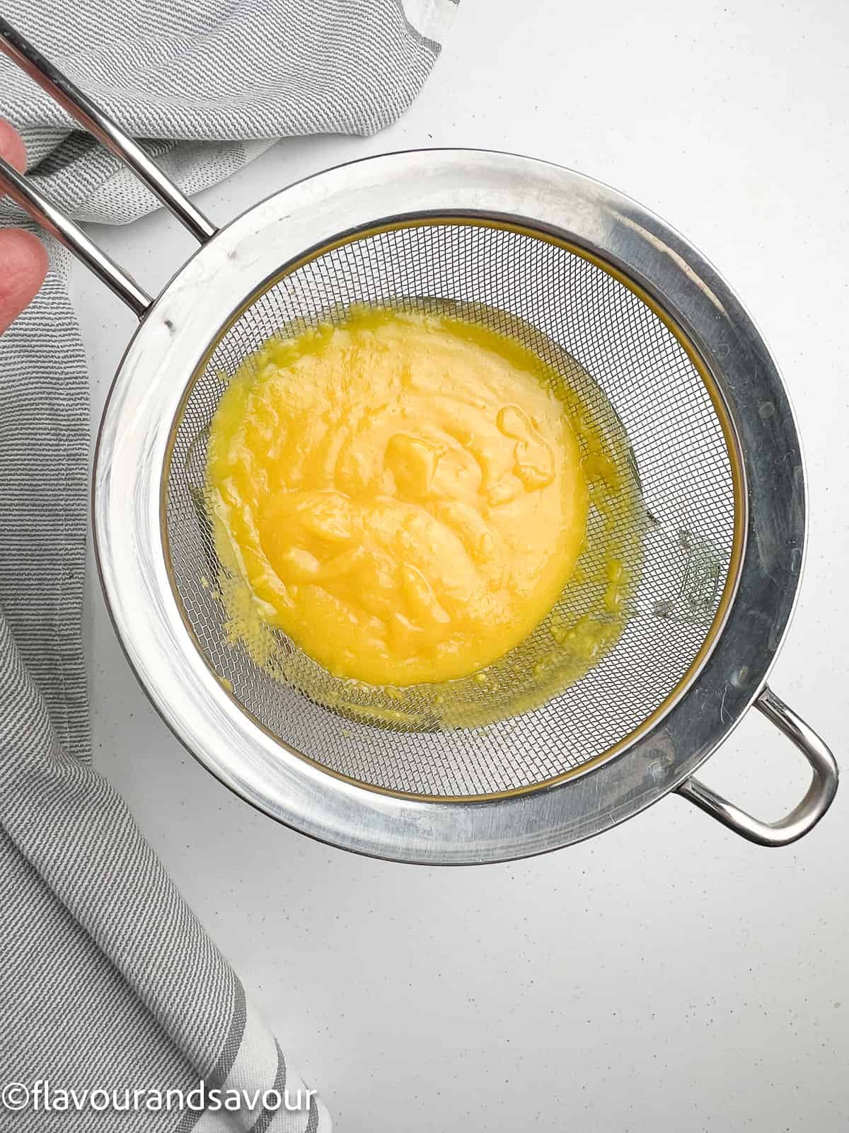 Straining lemon curd through a sieve.