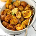 Crispy Lemon Oven Roasted Potatoes in an oval dish with a serving spoon