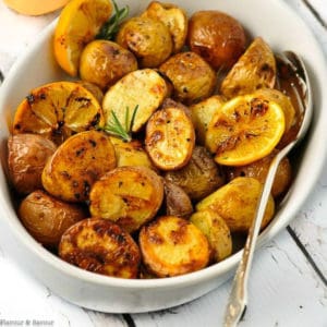 Crispy Lemon Oven Roasted Potatoes in an oval dish with a serving spoon