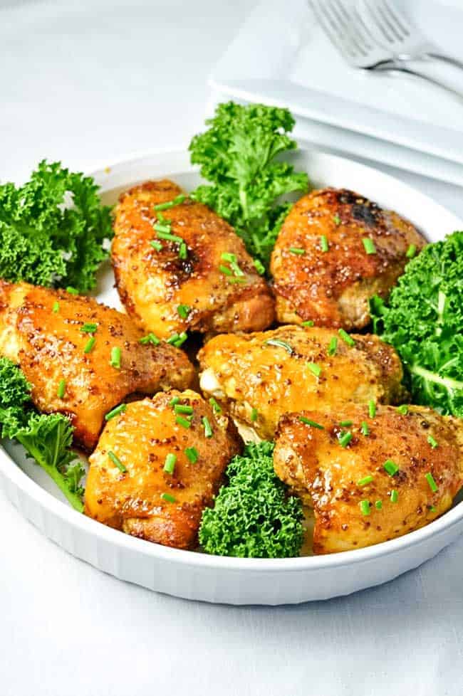 6 crispy baked chicken thighs on a round white platter. Honey Mustard Chicken with Turmeric is an easy one-pan chicken dish.