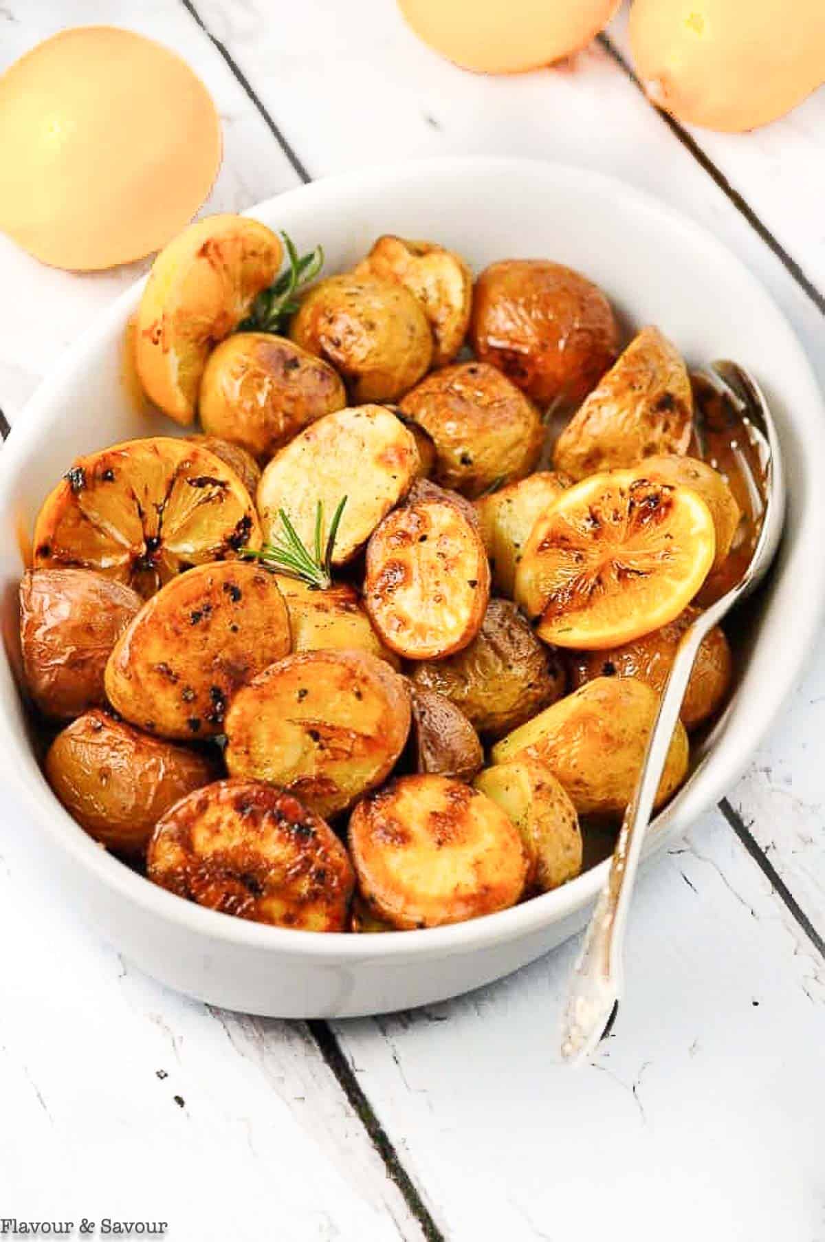 crispy lemon oven roasted potatoes in an oval white dish.