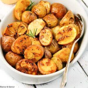 overhead view of a bowl of roast potatoes with lemon.