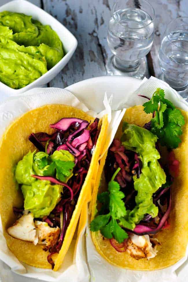 Tender flaky halibut cradled in a warm tortilla, smothered with a piquant red cabbage slaw, and topped with creamy guacamole---these halibut tacos make perfect portable hand food!
