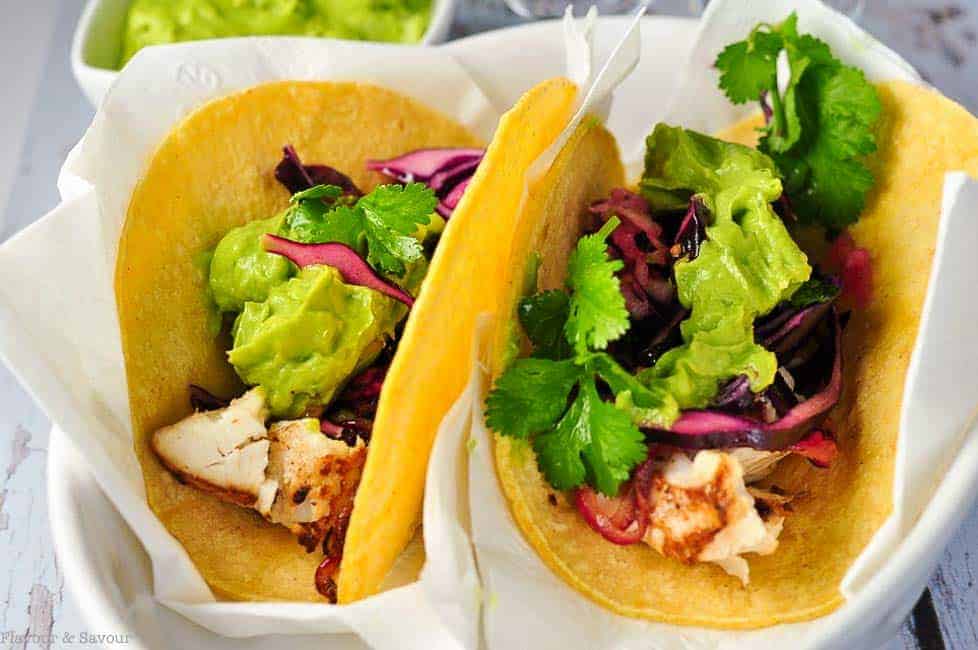 Tender flaky halibut cradled in a warm tortilla, smothered with a piquant red cabbage slaw, and topped with creamy guacamole---these halibut tacos make perfect portable hand food!