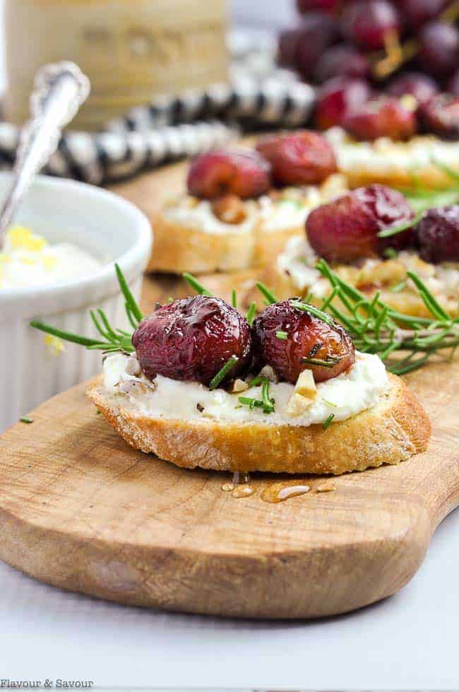 Side view of Roasted Grape and Goat Cheese Crostini on a serving board