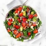 overhead view of a round white dish of Strawberry Kale Salad