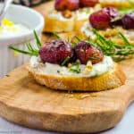 close up view of a crostini appetizer with roasted grapes and whipped goat cheese
