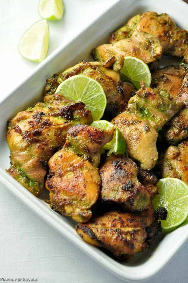 Easy Thai Baked Chicken cooked in a coconut milk marinade arranged in a serving dish with lime slices
