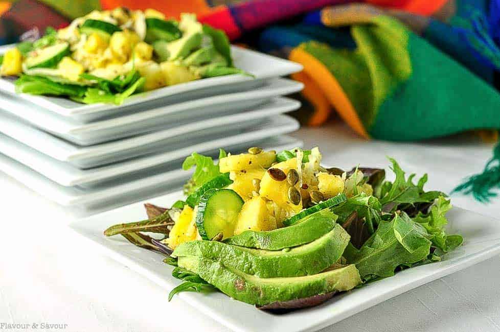 Pineapple Jicama Salad arranged on a square white plate with avocado slices