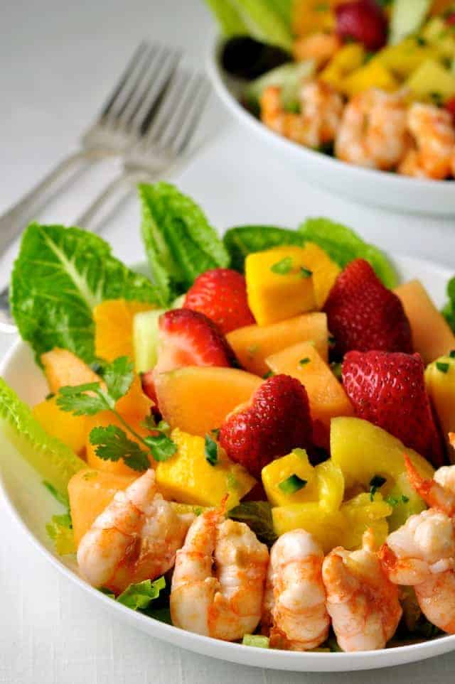 Southwestern Fruit Salad with grilled prawns in a white shallow bowl