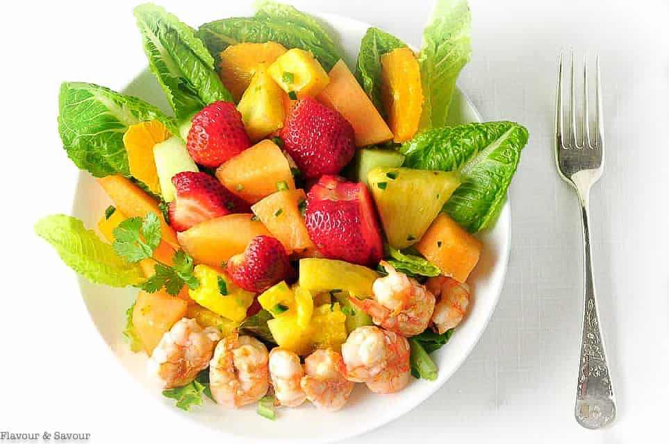 Overhead view of Shrimp Fruit Salad with strawberries and melon with a fork beside