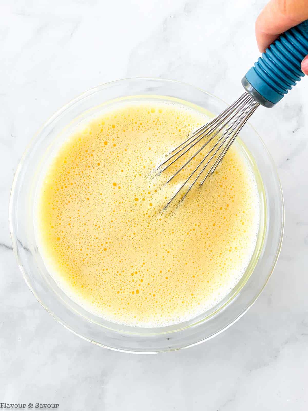 Whisked eggs in a bowl with a whisk.