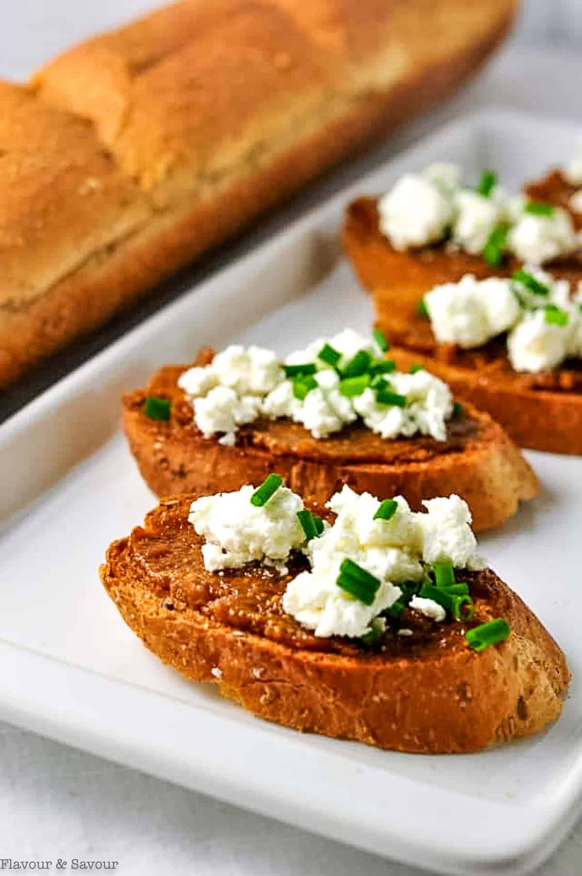 Three crostini appetizers with orange-fig spread and goat cheese crumbles.