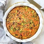 A baking dish with crustless zucchini carrot quiche with rosemary and bacon.