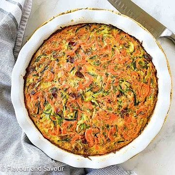 A baking dish with crustless zucchini carrot quiche with rosemary and bacon.