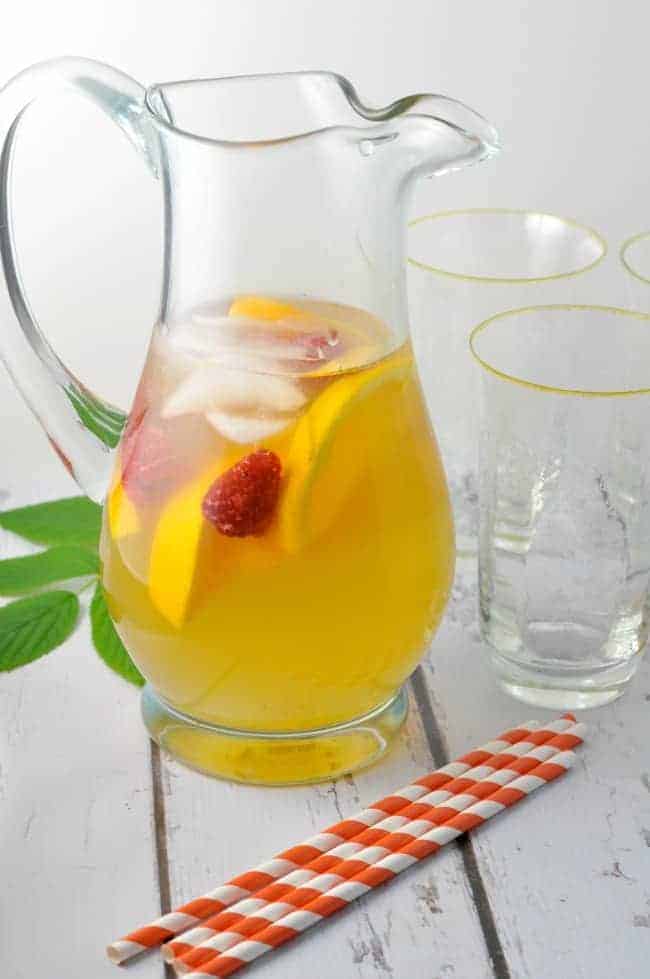 A pitcher of Raspberry Leaf, Rosemary and Orange Iced Tea with striped straws