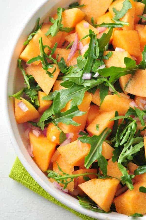 close up view of Cantaloupe Arugula Salad in a shallow round white dish