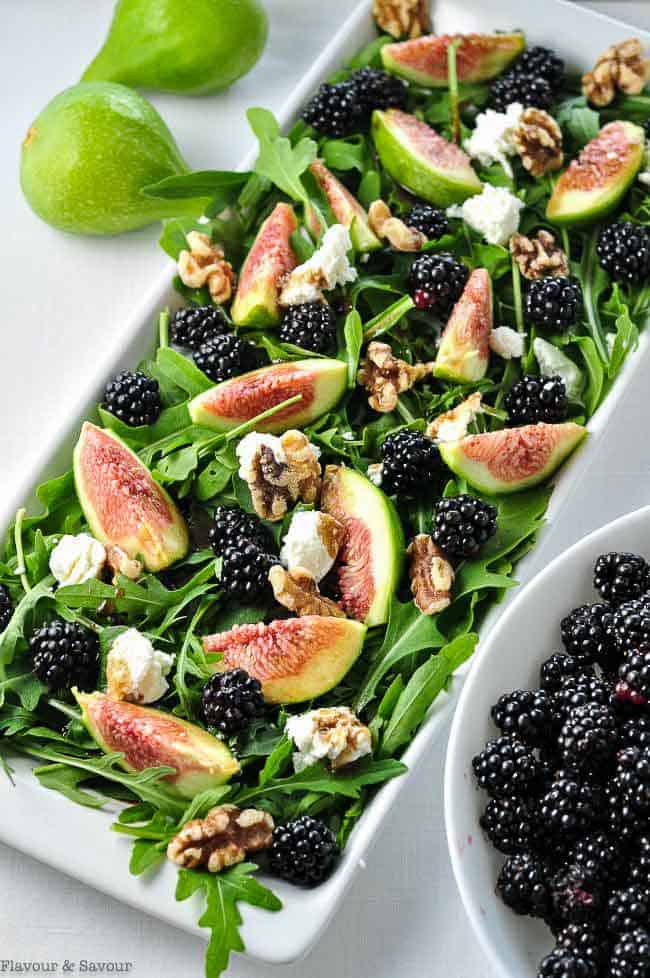 Fresh Fig Arugula Salad with Blackberries on a rectangular dish with a bowl of blackberries