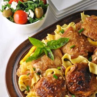 Lemon Garlic Chicken with Pasta and Herbs on a brown oval serving dish, garnished with basil.