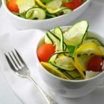 Two bowls of Zucchini Basil and Parmesan Salad with a fork.