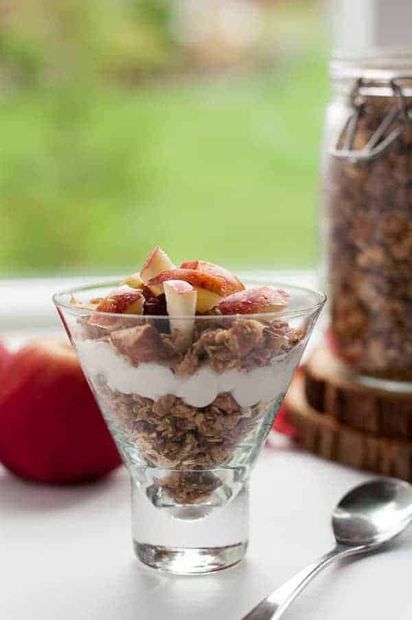 Granola layered in a jar with yogurt and fresh apples.