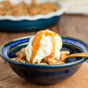 a bowl of apple crisp with ice cream and caramel sauce