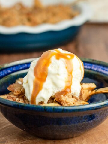 a bowl of apple crisp with ice cream and caramel sauce