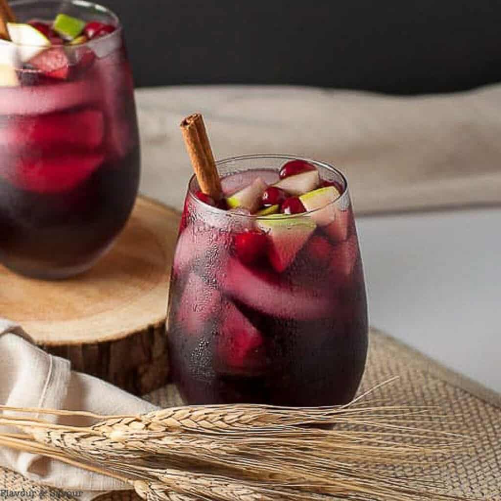 a glass of cranberry apple cider sangria with a cinnamon stick