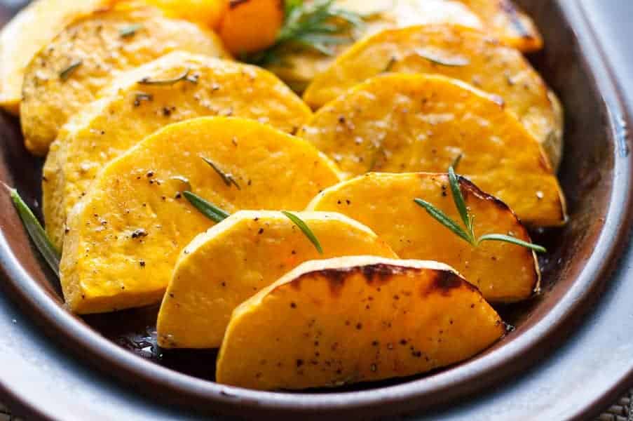 Roasted Butternut Squash with Fresh Rosemary and Lime on a dark brown platter.