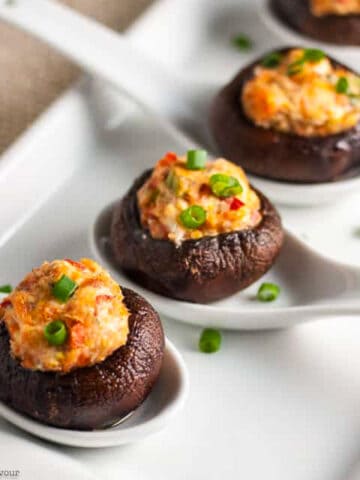 3 smoked salmon stuffed mushrooms on white ceramic spoons