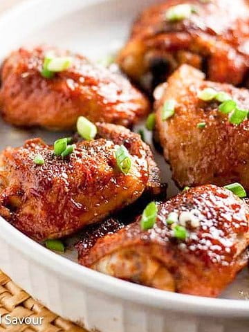 Chipotle honey-mustard glazed chicken thighs in a round white serving dish.