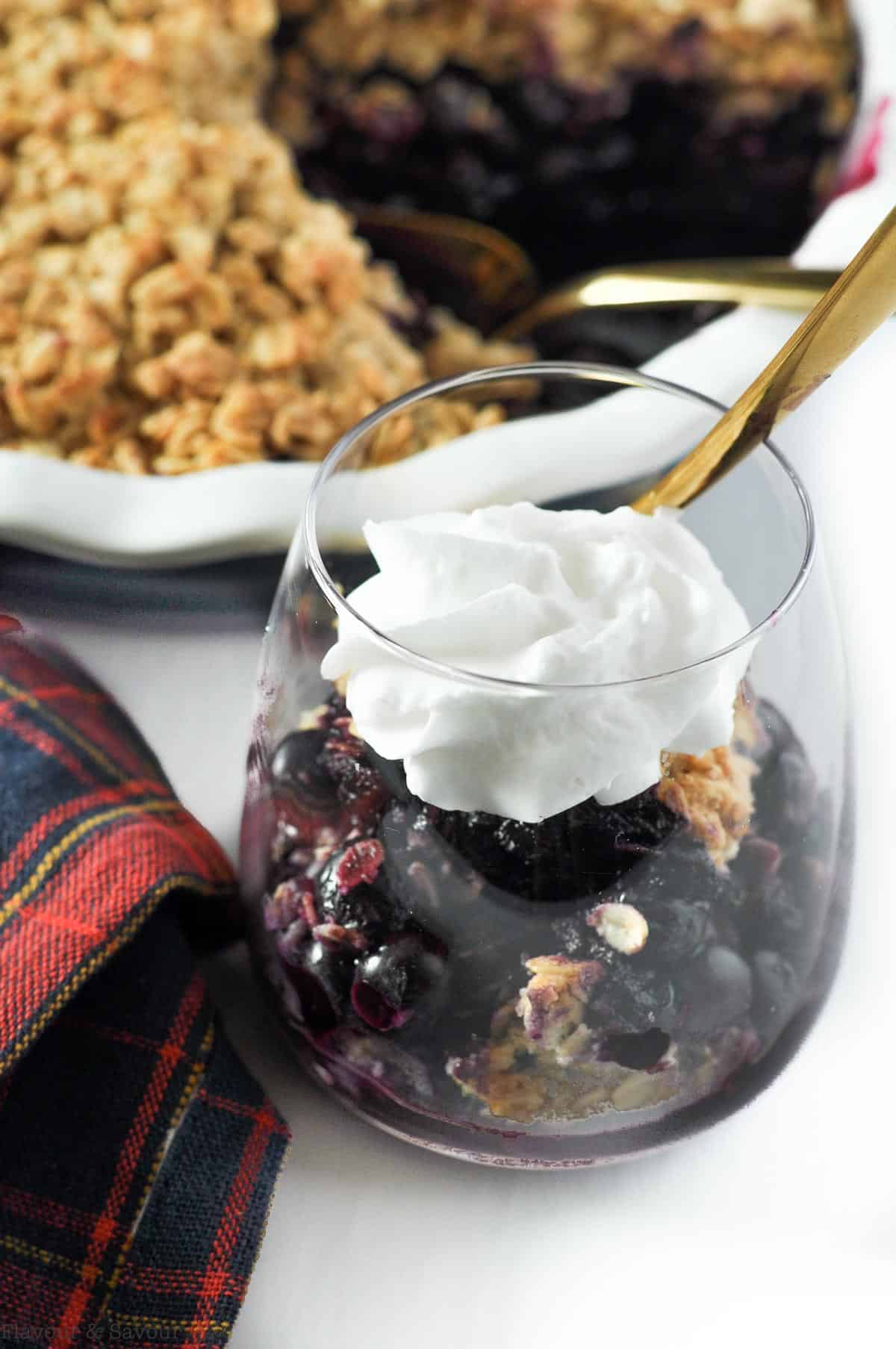 A dessert glass with bluebery Limoncello crisp topped with coconut whipped cream