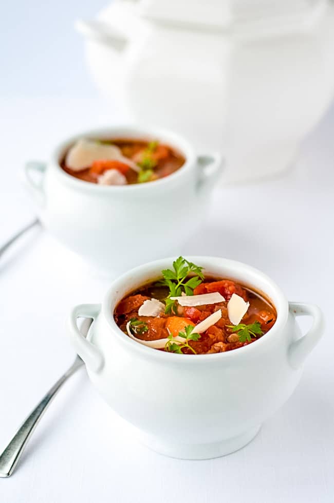 One-Pot Healthy and Hearty Tuscan Minestrone Soup in white soup tureens on a white background.