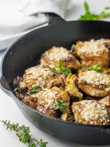 Baked Sun-dried Tomato and Artichoke Chicken thighs in cast iron skillet.