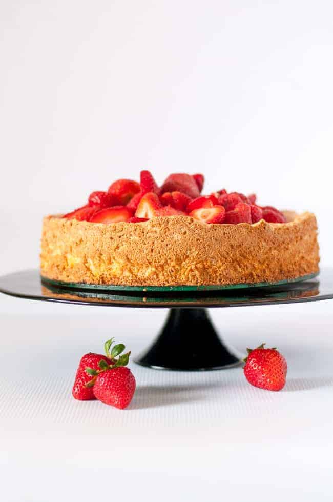 Gluten-Free Lemon Almond Cake with Strawberries on a black pedestal cake stand. www.flavourandsavour.com