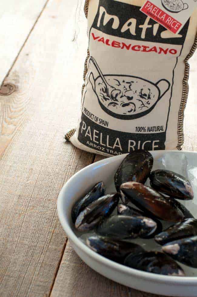 A bag of paella rice and a bowl of fresh mussels.