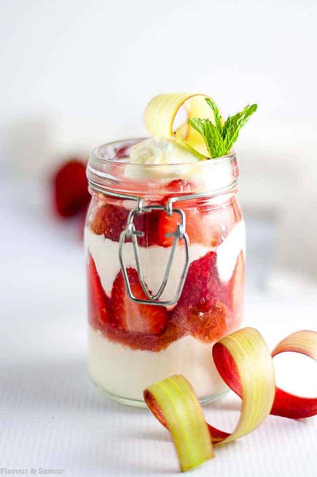 Skinny strawberry rhubarb parfait in a jar garnished with a rhubarb curl.