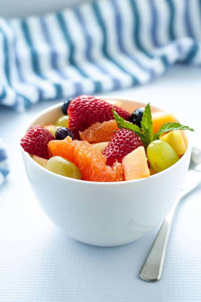 Tropical Fruit with Honey Mint Lime Syrup in a white bowl garnished with mint.