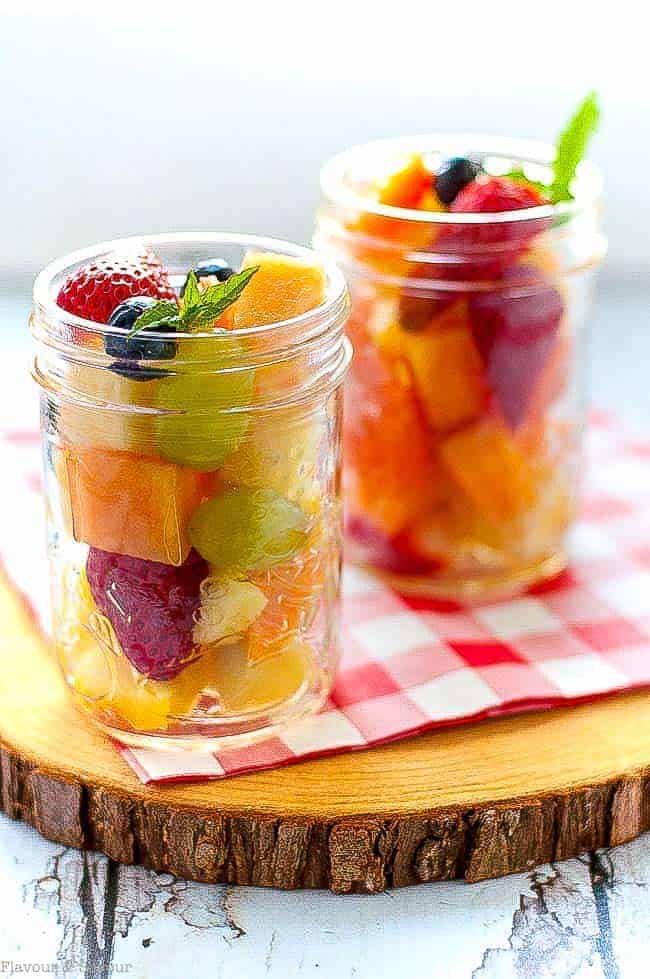 fruit salad in small jars on a slab of wood.